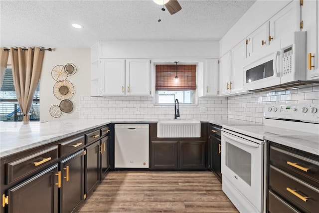 kitchen with decorative light fixtures, sink, white appliances, and white cabinetry