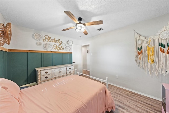 bedroom with ceiling fan, a textured ceiling, and hardwood / wood-style flooring