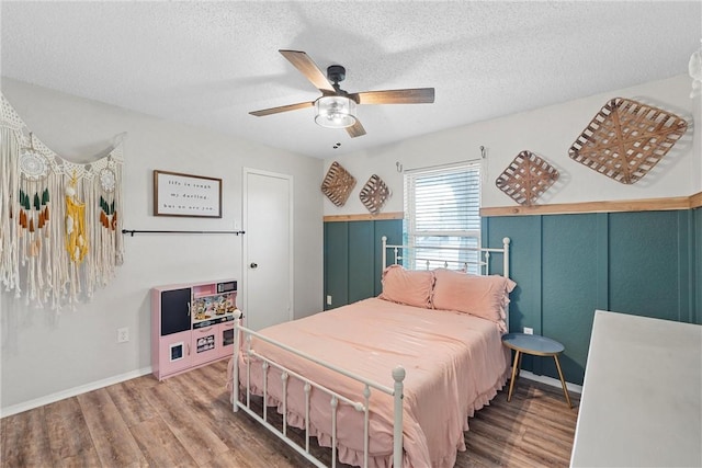 bedroom featuring ceiling fan, hardwood / wood-style floors, and a textured ceiling