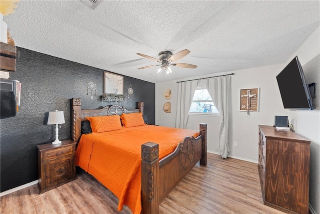 bedroom featuring light wood-type flooring, ceiling fan, and a textured ceiling