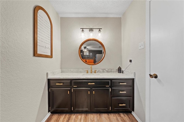 bathroom with hardwood / wood-style floors, vanity, and a textured ceiling