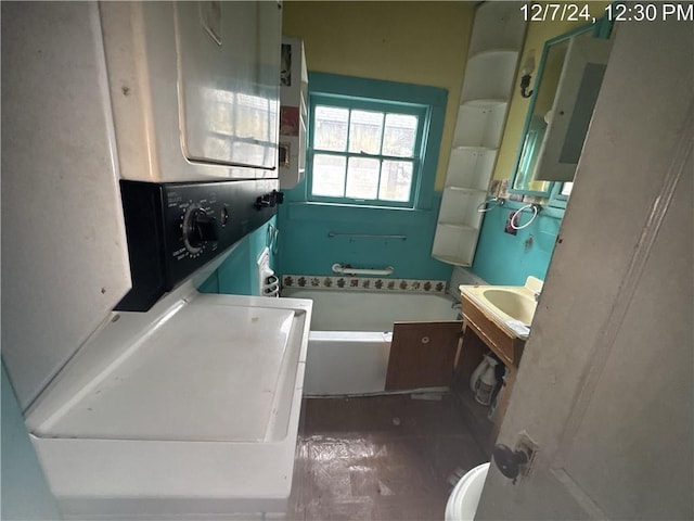 bathroom featuring a bath, toilet, stacked washer / drying machine, and wood-type flooring