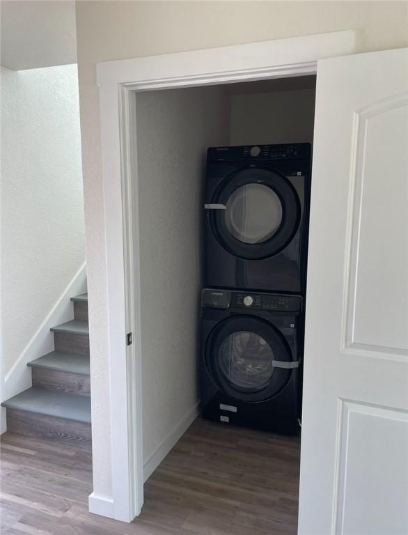 laundry area with stacked washer / drying machine and hardwood / wood-style floors