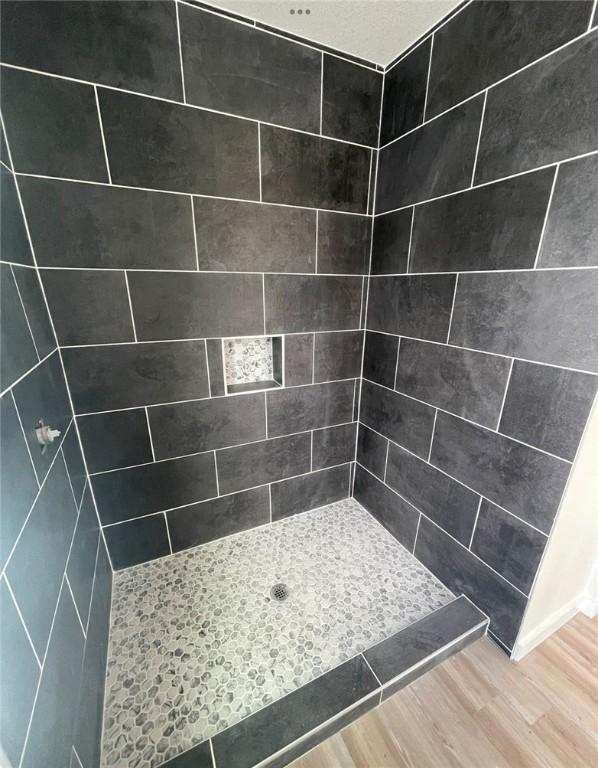 bathroom with wood-type flooring and a tile shower