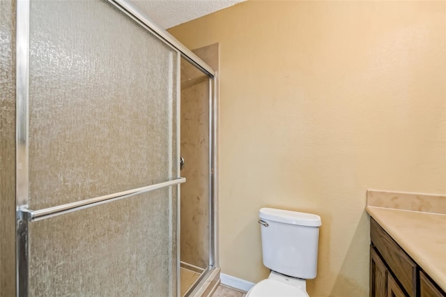 bathroom with vanity, a textured ceiling, toilet, and walk in shower