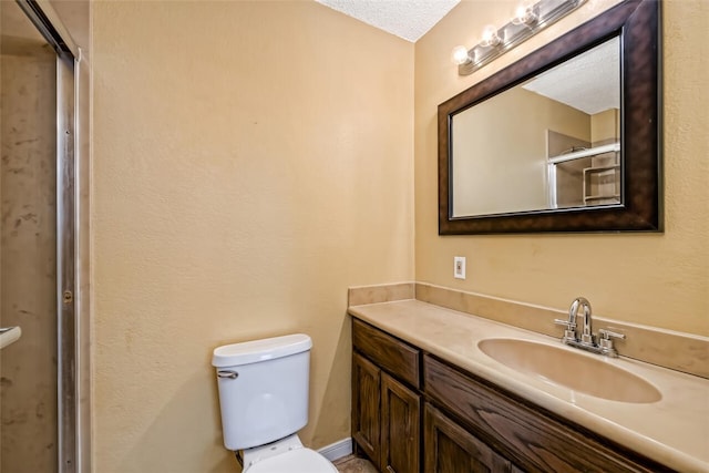 bathroom with vanity, toilet, a shower with shower door, and a textured ceiling