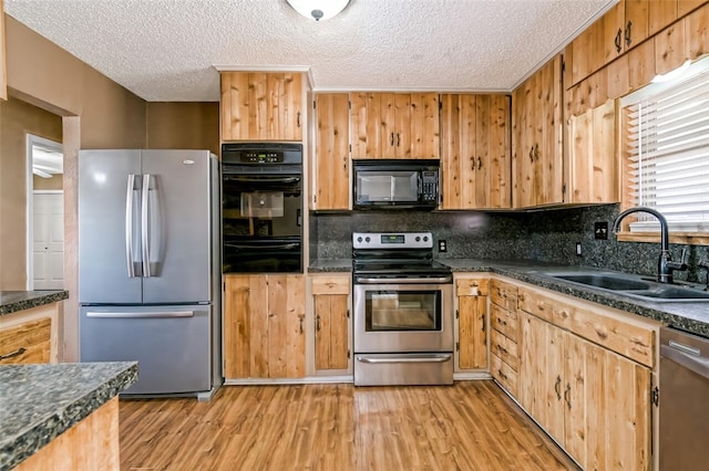 kitchen with decorative backsplash, light wood-type flooring, a textured ceiling, sink, and black appliances