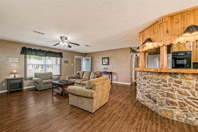 living room with a textured ceiling, dark hardwood / wood-style floors, and ceiling fan