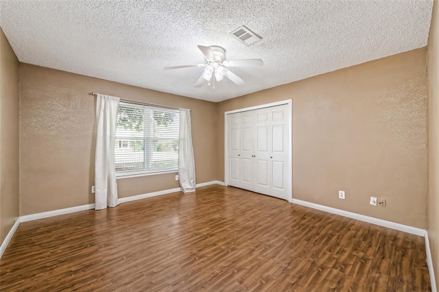 unfurnished bedroom featuring a textured ceiling, ceiling fan, a closet, and dark hardwood / wood-style floors