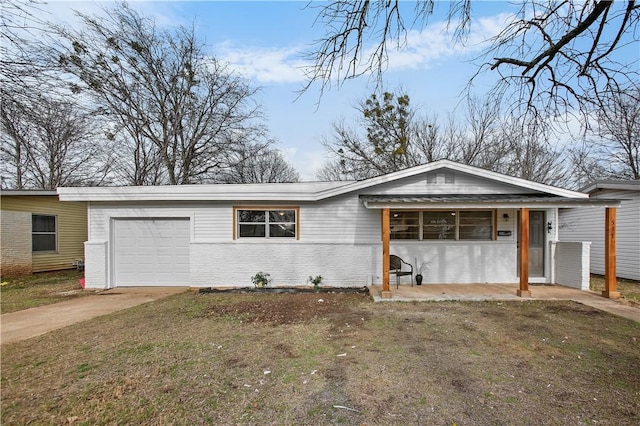 view of front of property featuring an attached garage, covered porch, brick siding, concrete driveway, and a front yard