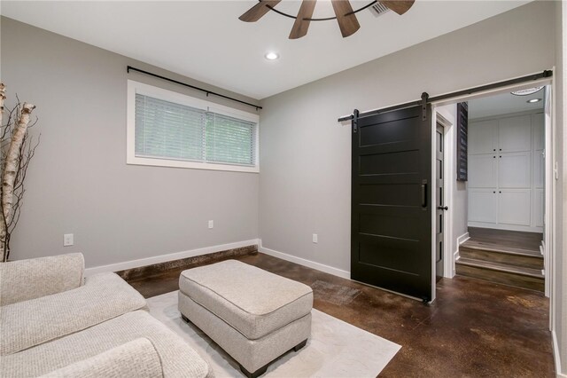 sitting room featuring ceiling fan and a barn door