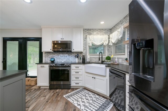 kitchen featuring sink, stainless steel appliances, light hardwood / wood-style flooring, backsplash, and white cabinets