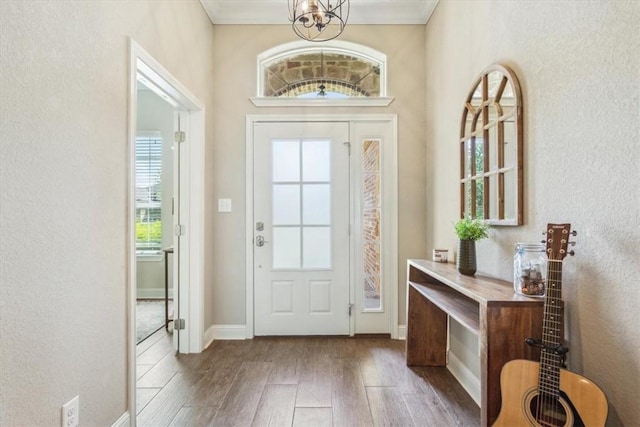 foyer entrance featuring crown molding, hardwood / wood-style floors, and an inviting chandelier