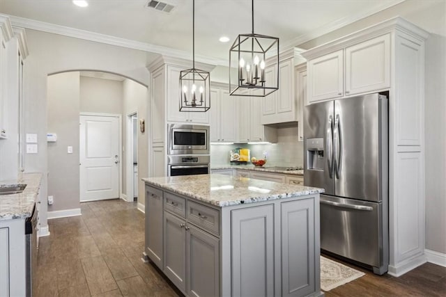 kitchen with dark hardwood / wood-style flooring, a center island, hanging light fixtures, and appliances with stainless steel finishes