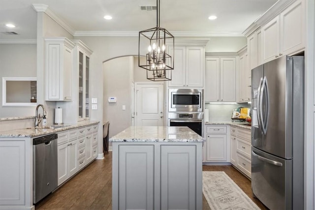 kitchen featuring dark wood-type flooring, white cabinets, hanging light fixtures, light stone countertops, and appliances with stainless steel finishes