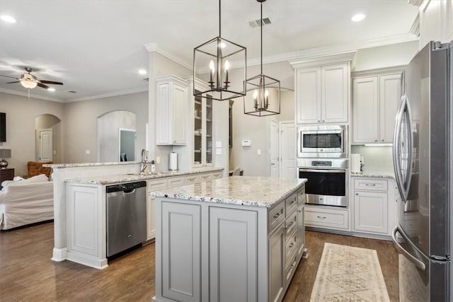 kitchen with kitchen peninsula, stainless steel appliances, a kitchen island, pendant lighting, and white cabinetry