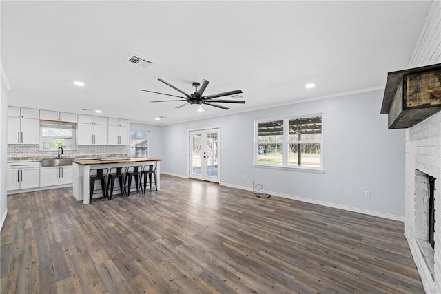 unfurnished living room featuring a fireplace, plenty of natural light, ornamental molding, and ceiling fan