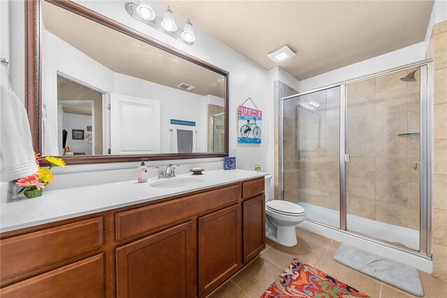 full bath featuring toilet, vanity, a shower stall, and tile patterned floors