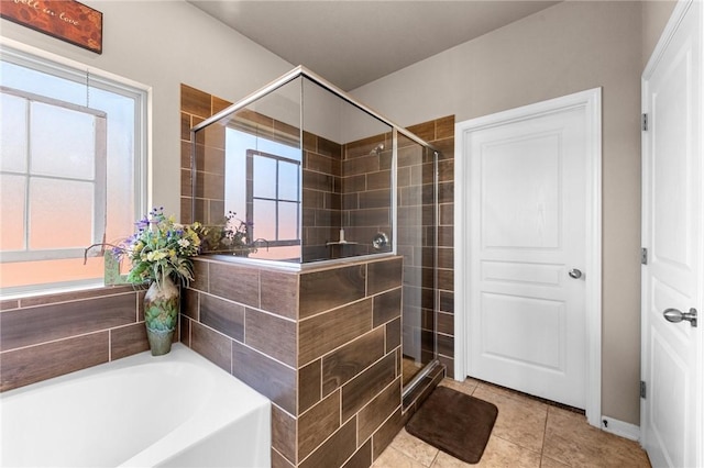 full bath featuring a stall shower, tile patterned flooring, a garden tub, and a wealth of natural light