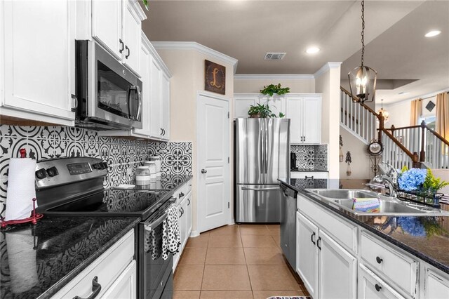 kitchen with a sink, white cabinets, appliances with stainless steel finishes, dark stone counters, and decorative light fixtures