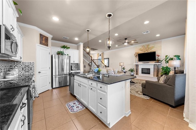 kitchen with white cabinets, a kitchen island with sink, appliances with stainless steel finishes, and open floor plan