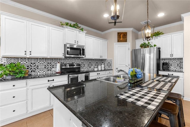 kitchen with light tile patterned floors, white cabinets, appliances with stainless steel finishes, a kitchen island with sink, and a sink