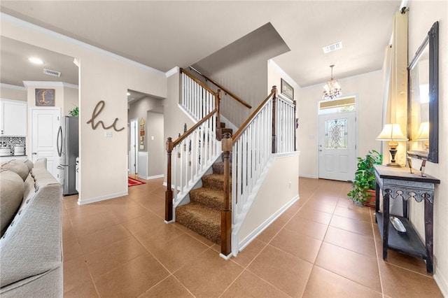 entrance foyer with ornamental molding, tile patterned flooring, visible vents, and stairway