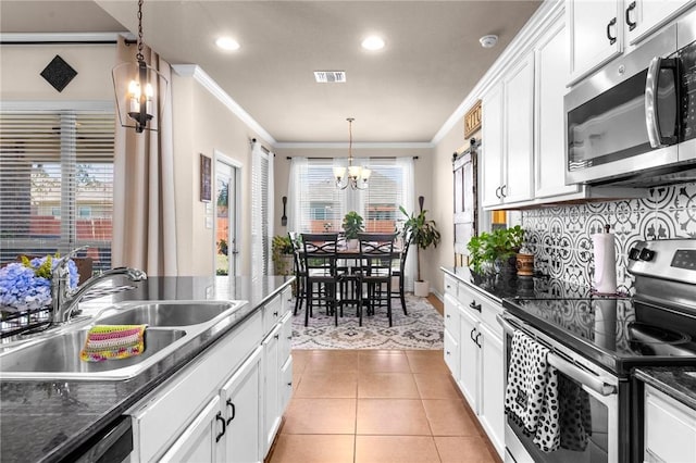 kitchen with light tile patterned floors, stainless steel appliances, hanging light fixtures, white cabinets, and a sink