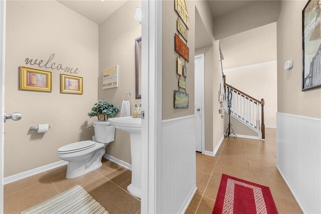 bathroom featuring toilet, a wainscoted wall, and tile patterned floors