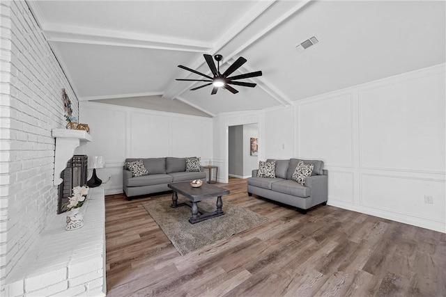 living room featuring lofted ceiling with beams, ceiling fan, wood-type flooring, and a fireplace