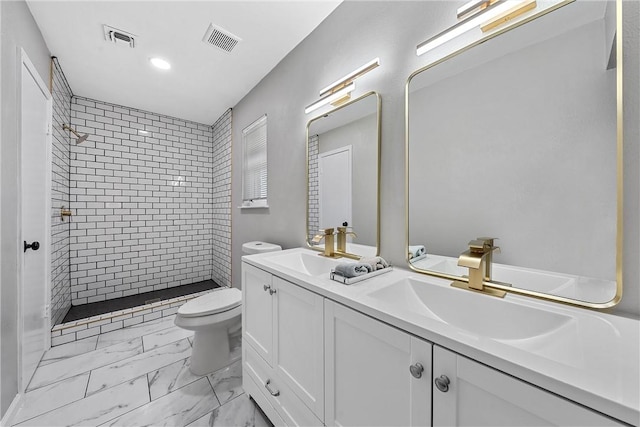 bathroom featuring a tile shower, vanity, and toilet