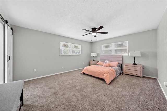 bedroom with a textured ceiling, a barn door, carpet floors, and ceiling fan