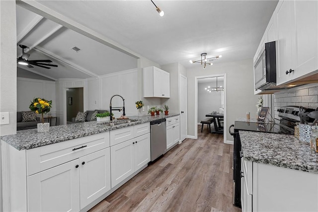 kitchen with kitchen peninsula, white cabinets, stainless steel appliances, and light hardwood / wood-style floors