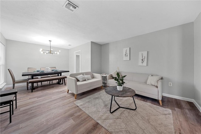 living room with light wood-type flooring and a chandelier