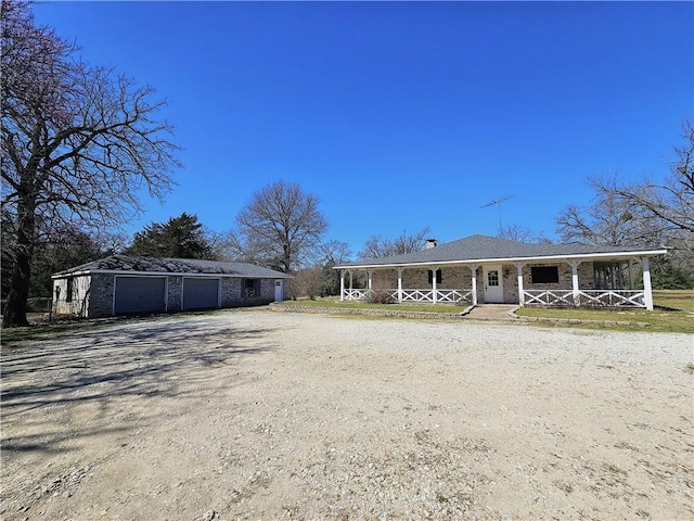 exterior space featuring an outdoor structure, covered porch, and dirt driveway