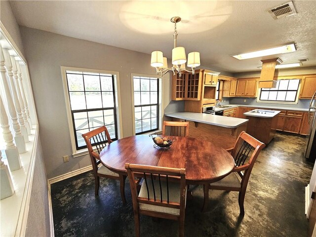 dining space with visible vents, a notable chandelier, a textured ceiling, concrete floors, and baseboards