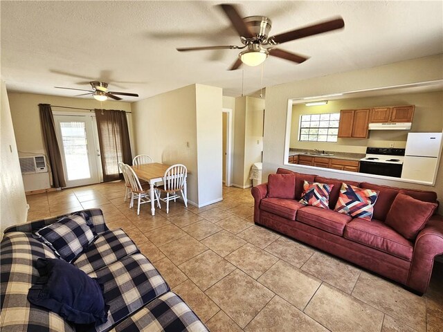 living room featuring baseboards, ceiling fan, a wall mounted air conditioner, light tile patterned floors, and a textured ceiling