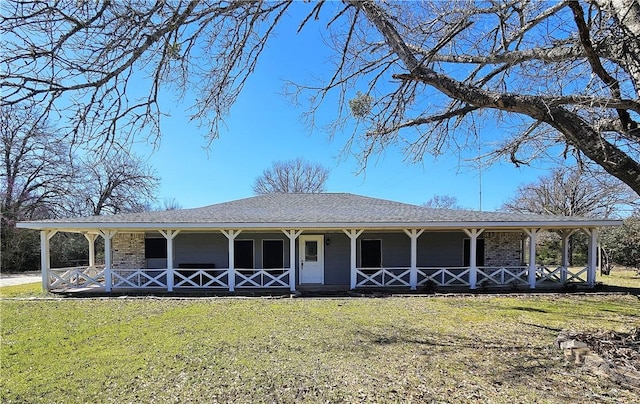 farmhouse-style home with roof with shingles, covered porch, and a front lawn