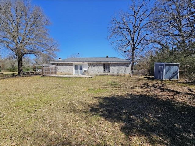 rear view of house with fence, a yard, a storage shed, an outdoor structure, and brick siding