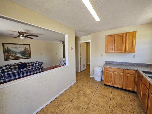 kitchen with ceiling fan, light tile patterned flooring, brown cabinetry, and a sink