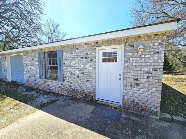 doorway to property with a garage and brick siding