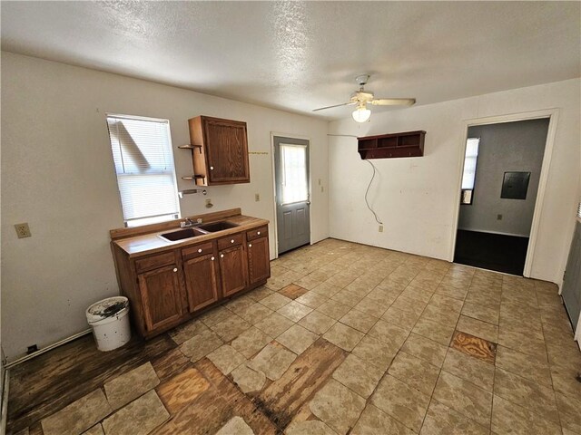 kitchen featuring a sink, light countertops, a textured ceiling, a ceiling fan, and open shelves