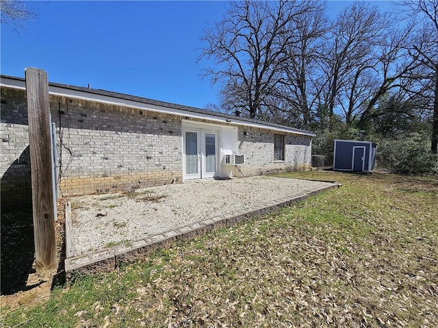 back of property with a patio, an outbuilding, cooling unit, french doors, and brick siding