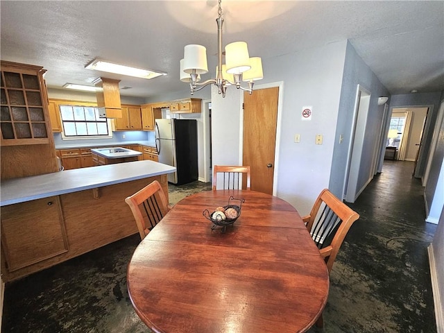 dining room with concrete floors, baseboards, a textured ceiling, and an inviting chandelier