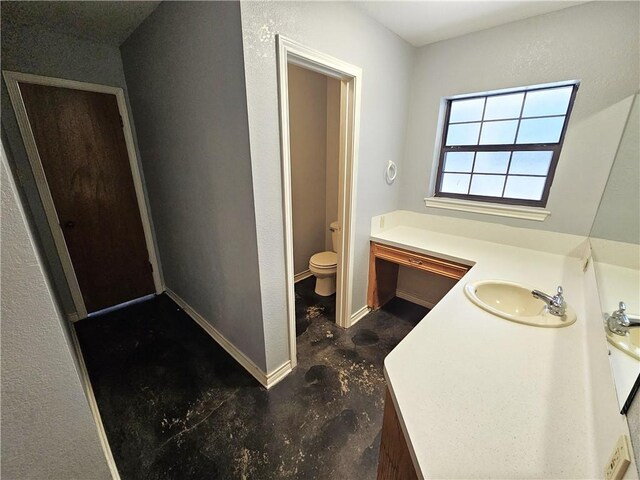 bathroom featuring unfinished concrete floors, toilet, vanity, and baseboards