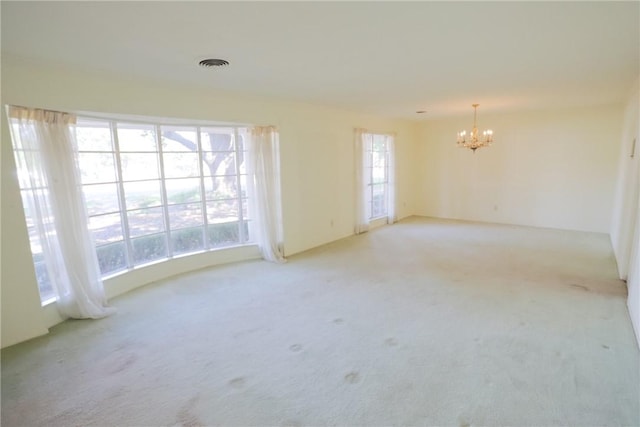 empty room featuring light carpet and an inviting chandelier