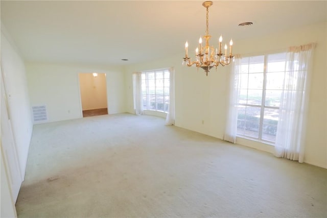 unfurnished room with a healthy amount of sunlight, light carpet, and an inviting chandelier