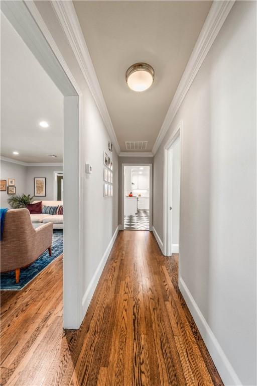 corridor featuring wood-type flooring and ornamental molding