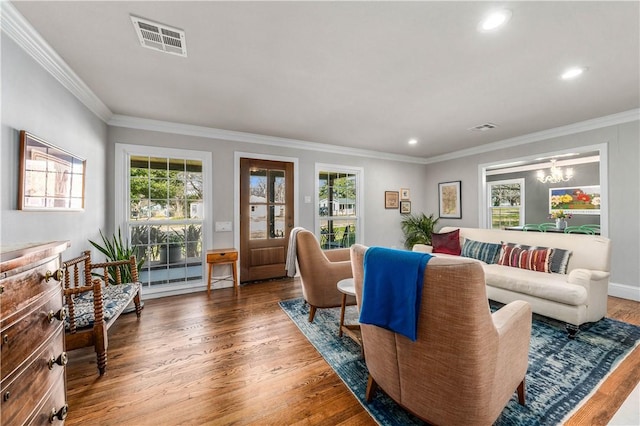 living room featuring a chandelier, crown molding, plenty of natural light, and wood-type flooring