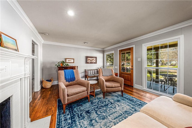 living area with hardwood / wood-style floors, ornamental molding, and a tile fireplace